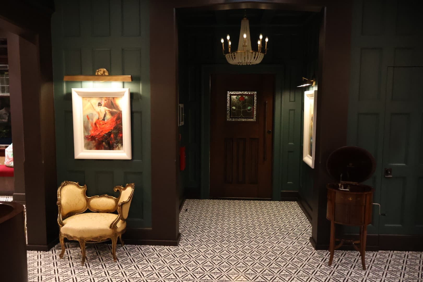 Elegant dark green hallway with chandelier and patterned tile floor