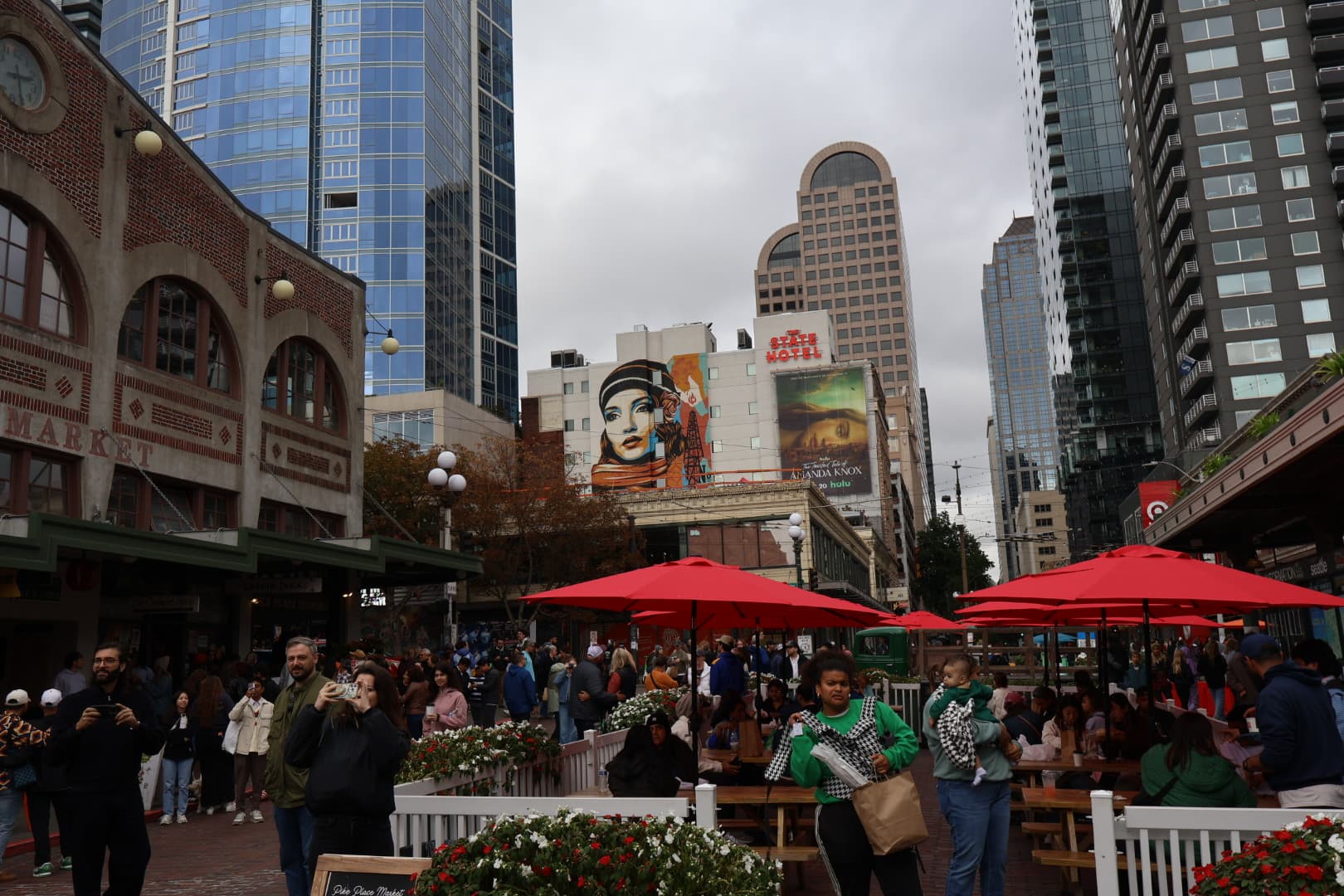 Bustling Pike Place Market area with red umbrellas and city skyline